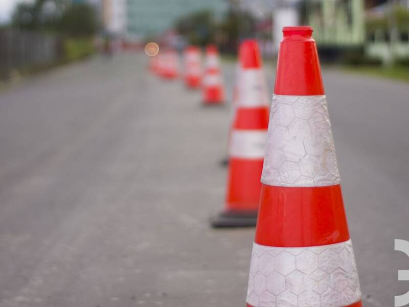 Eine asphaltierte Straße in grau mit orang-weißen Leitkegeln